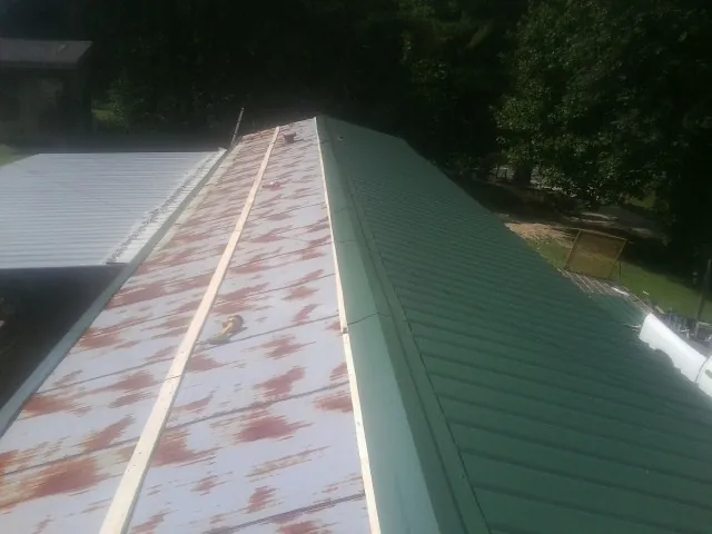 Old rusted panels beside newly installed green metal roofing — Wind Damage Roof Repair by Roofing Brothers in Charleroi