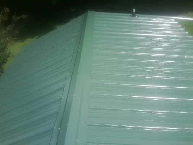 New green metal panels meeting at the ridge of a roof — Flat Roof Repair work by our crew in Charleroi