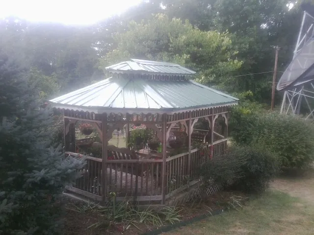 Green metal roof on a backyard gazebo surrounded by garden beds in Charleroi