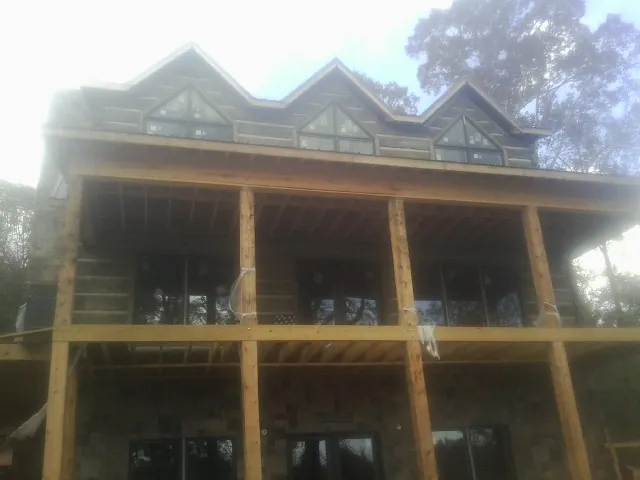 Dormers and porch framing on a large log home under construction — Roof Coating work by our crew in Charleroi