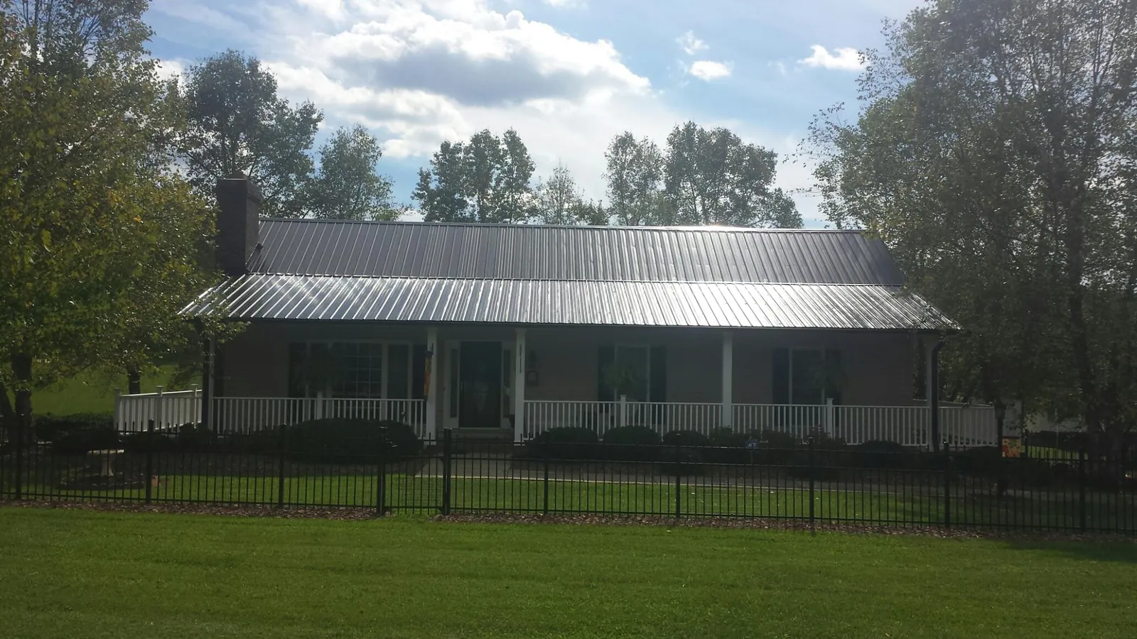 Gray metal roof on a brick ranch with a full width front porch — Gutter Guard Installation work by our crew in Charleroi