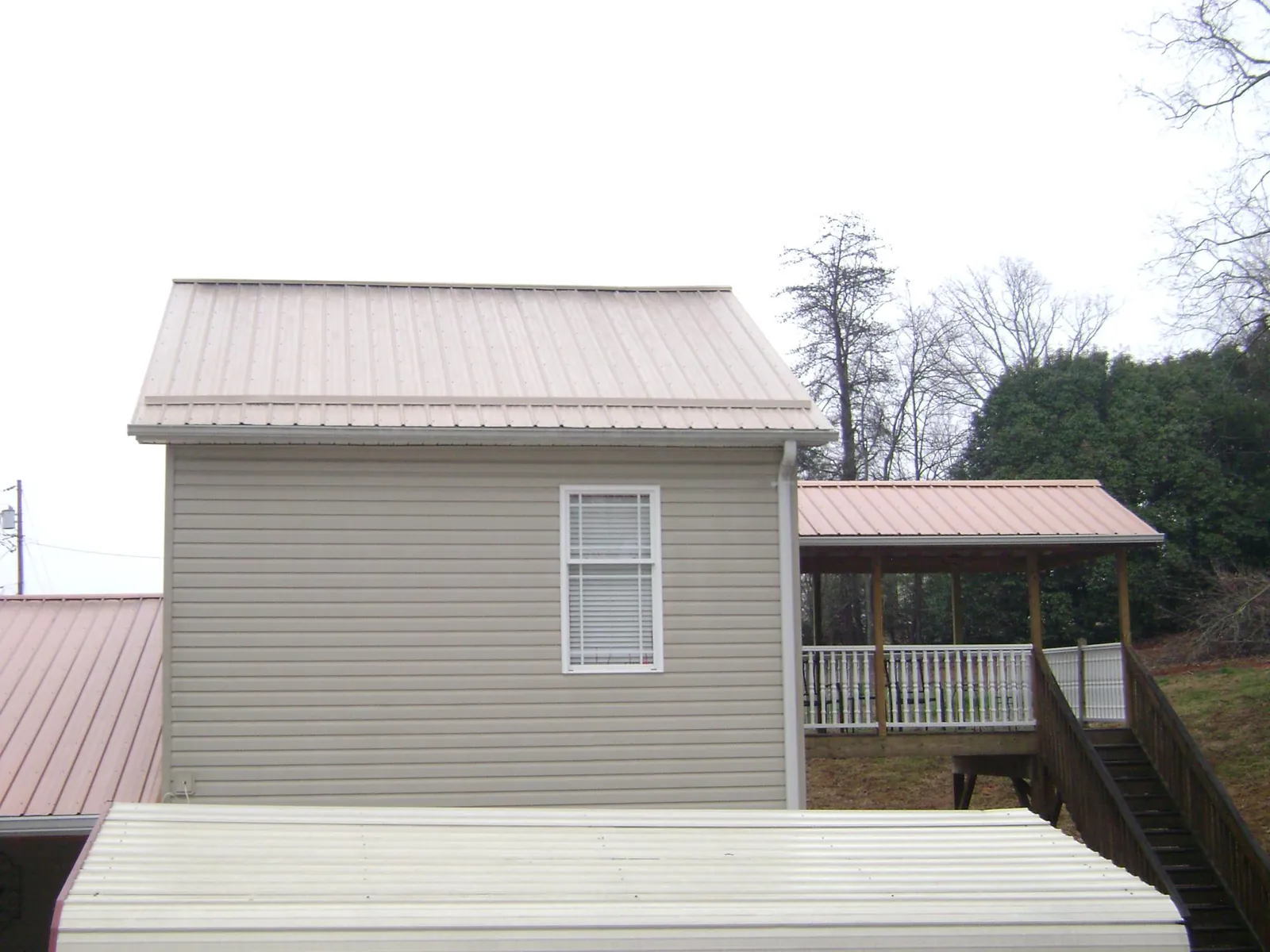Tan metal roofs on a two story addition and attached porch, from a Roof Replacement job in Charleroi