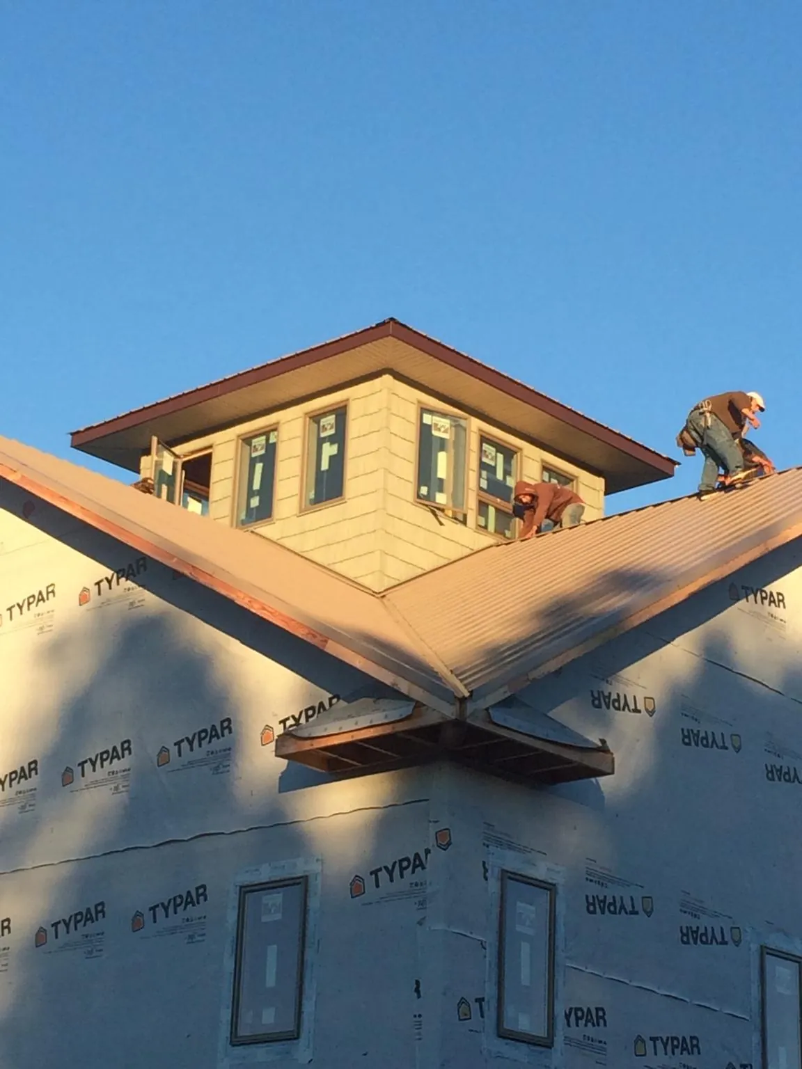 Roofers working around a rooftop cupola on a new metal roof at sunset — Roof Waterproofing in Charleroi by Roofing Brothers